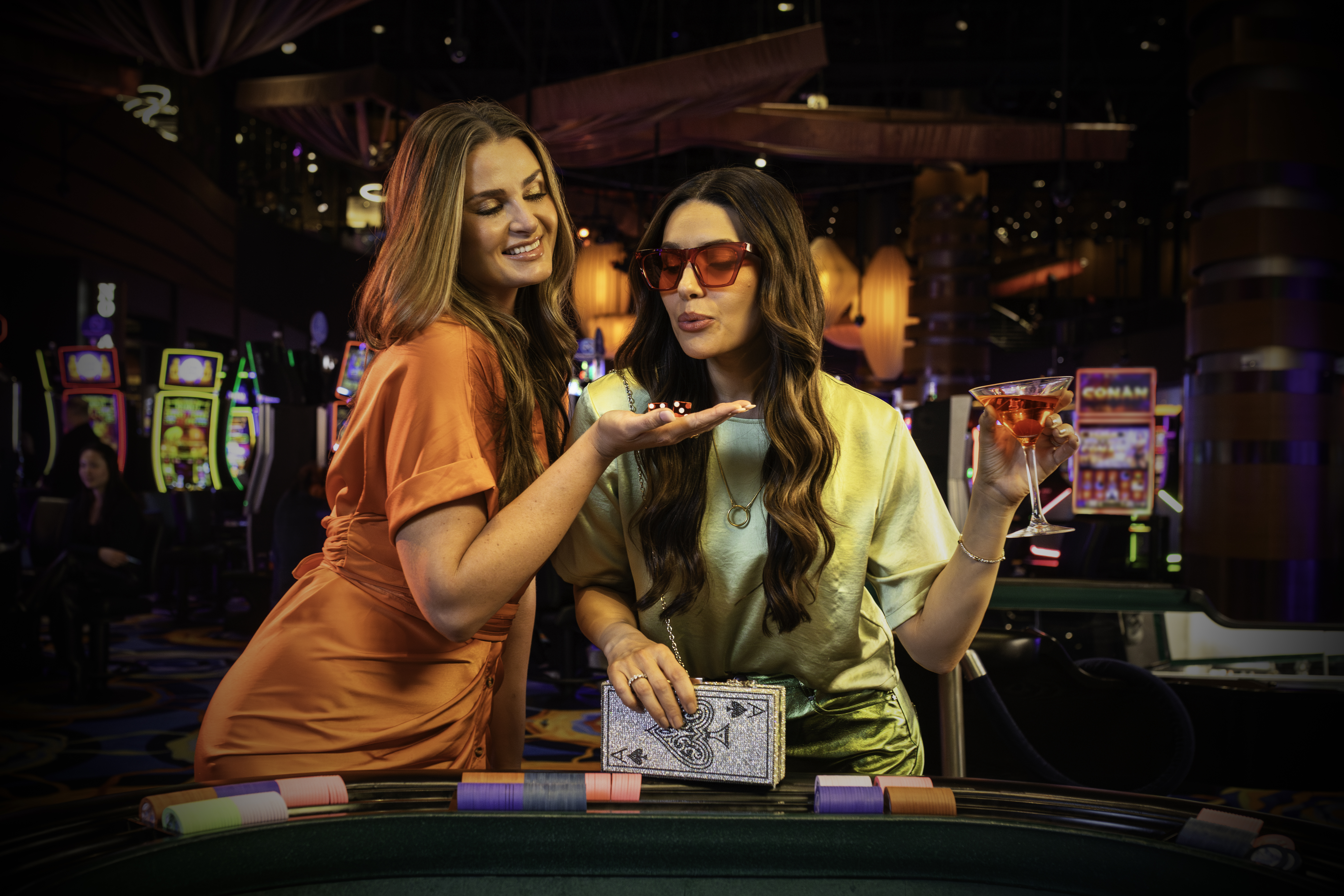 Two women enjoying a night of gaming and cocktails at Ocean Casino Resort, celebrating with laughter and luck.