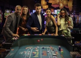 Five stylish guests celebrate a thrilling dice roll at Ocean Casino Resort’s vibrant gaming floor, surrounded by colorful slot machines and glowing lights.